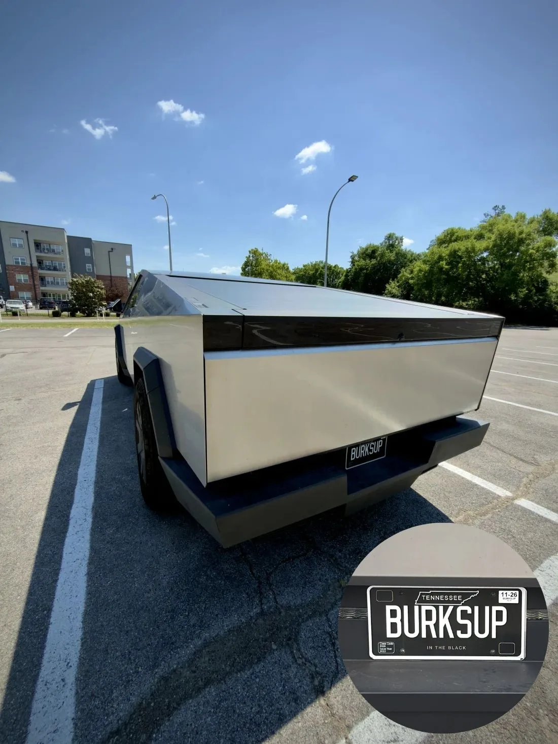 A Tesla Cybertruck in a parking lot with a BURKSUP license plate.